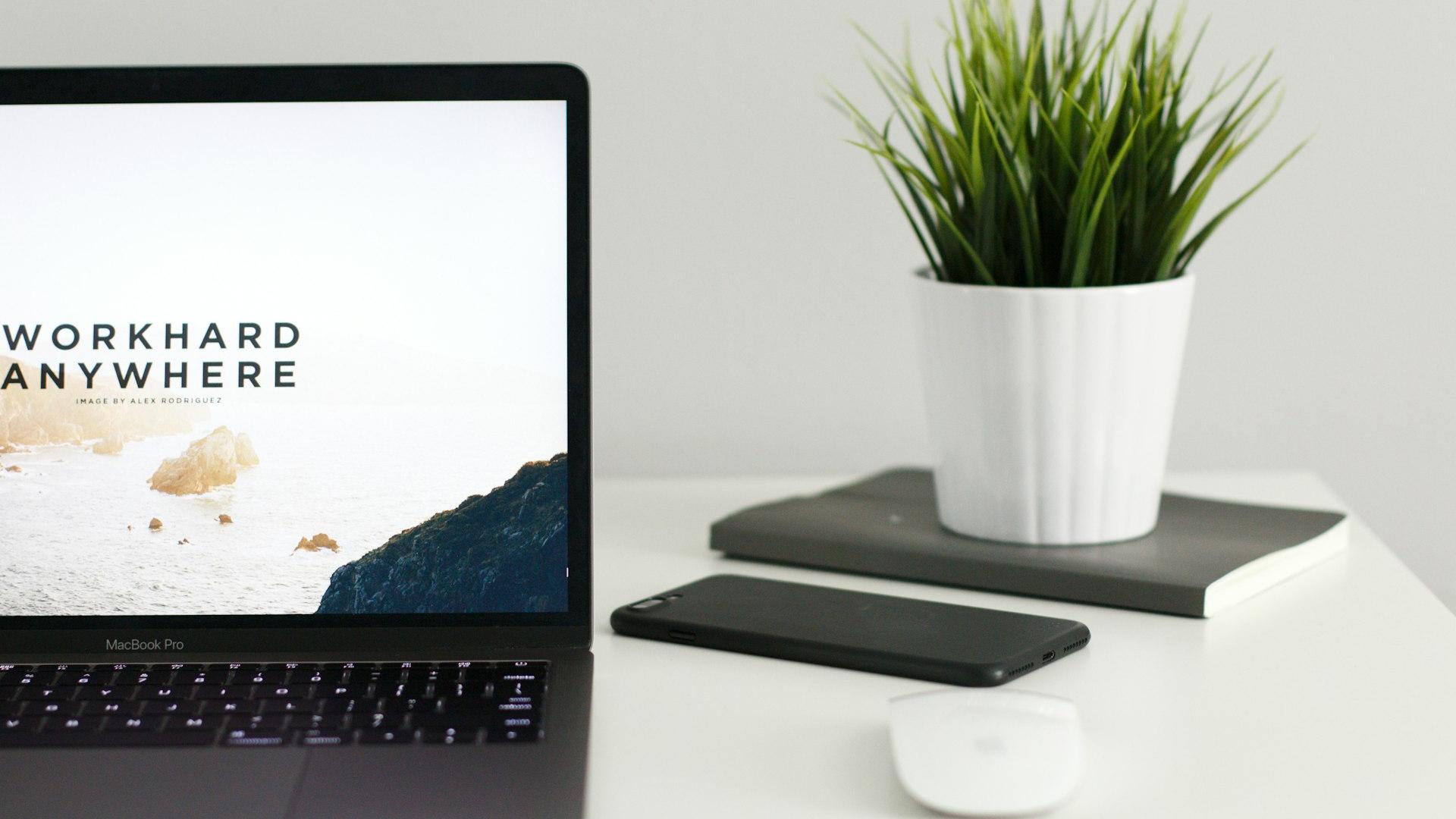 MacBook Pro near green potted plant on table